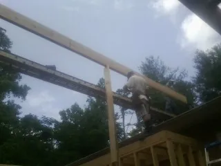 Carpenter setting a ridge beam over a new addition frame — Ice Dam Removal by Roofing Brothers in Grinnell