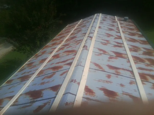 Rusted metal roof panels with new wood purlins before replacement — Storm Damage Roof Repair in Grinnell by Roofing Brothers