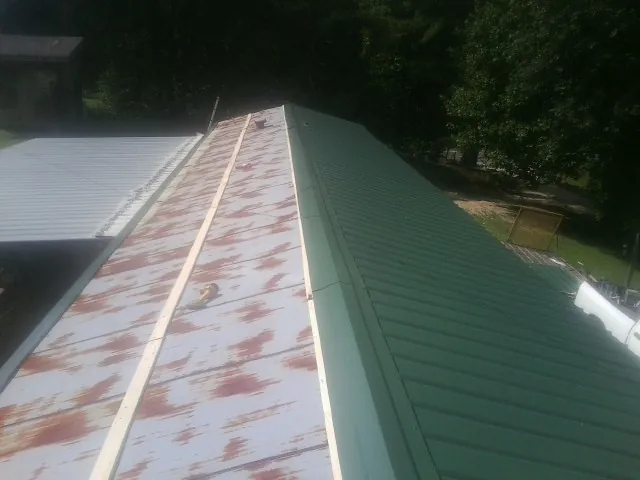 Old rusted panels beside newly installed green metal roofing — Wind Damage Roof Repair by Roofing Brothers in Grinnell