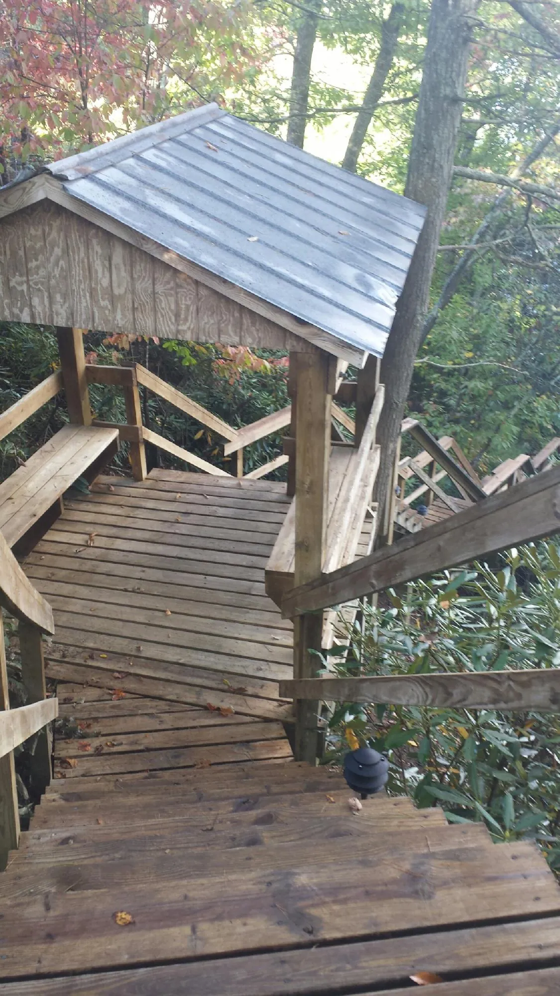 Metal roofed shelter over wooden steps on a wooded walkway — Skylight Repair & Installation work by our crew in Grinnell